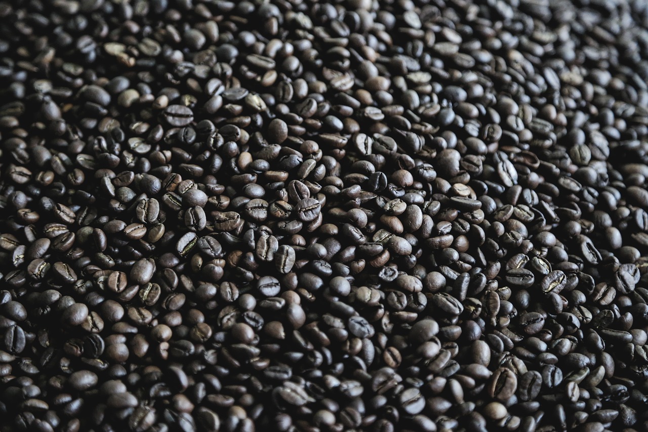 a pile of coffee beans sitting on top of a table, a macro photograph, pexels, background image, 4k high res, black textured, beautiful sunny day