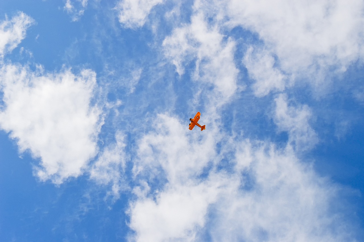 an airplane that is flying in the sky, a stock photo, fine art, some orange and blue, lie on white clouds fairyland, flying drones, bright sunny summer day