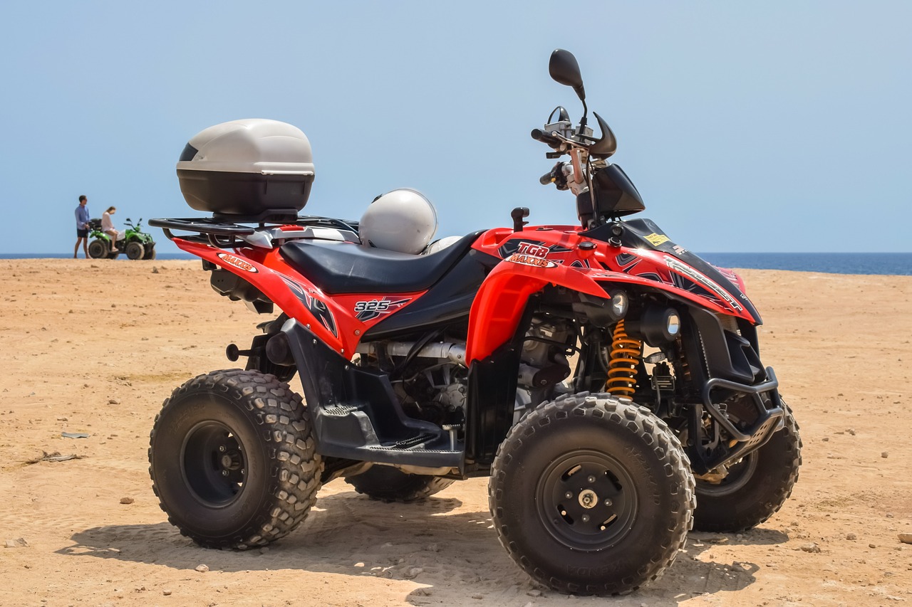 a red four wheeler atv parked on a sandy beach, a portrait, shutterstock, costa blanca, featuring engine, fully body photo