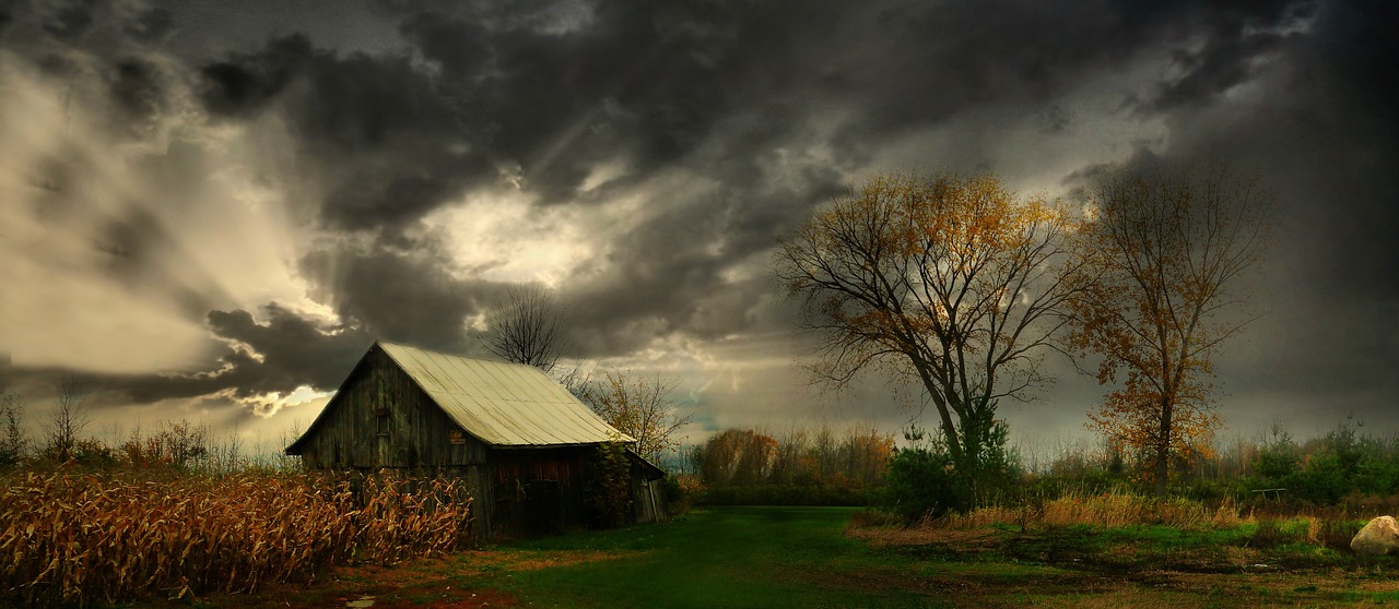 a barn in the middle of a field under a cloudy sky, flickr, romanticism, autumn light, dark shadowy surroundings, screensaver, shed