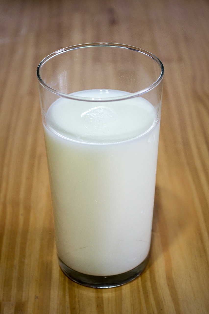 a glass of milk sitting on top of a wooden table, flickr, wikimedia, straight smooth vertical, really long, in style of thawan duchanee