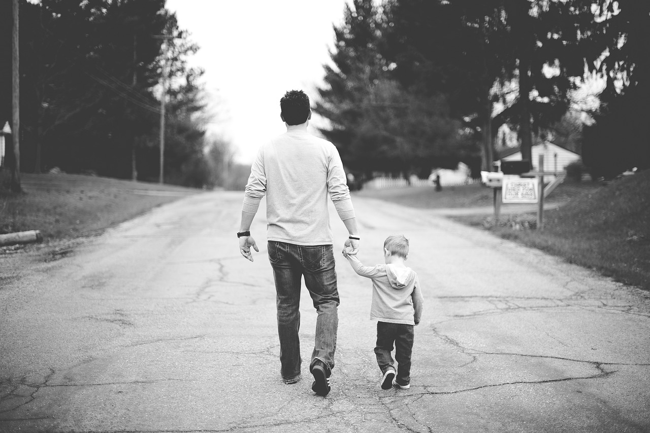 a man and a small child walking down a street, a black and white photo, pexels, symbolism, denim, dad bod, precious moments, istockphoto