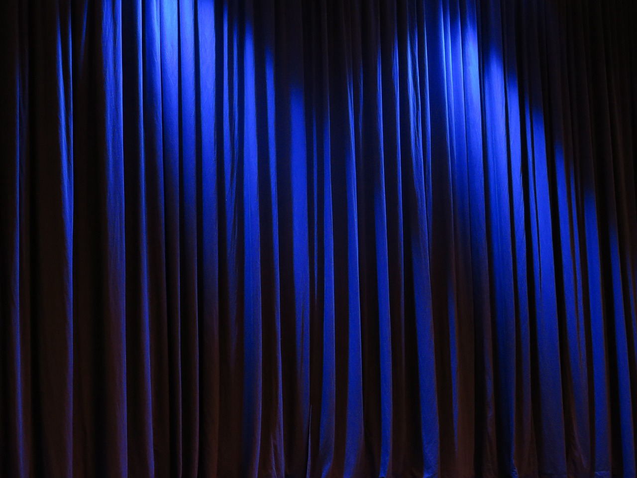 a man standing in front of a blue curtain, pexels, baroque, ( ( stage lights ) ), corinne day, blue velvet, closeup photo