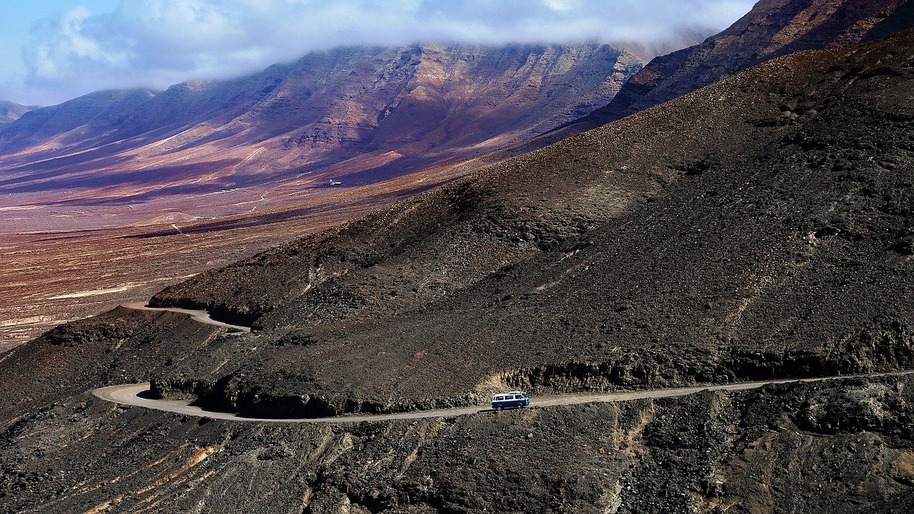 a car driving down a winding mountain road, a photo, by Andrei Kolkoutine, flickr, hurufiyya, lava field, microbus, tatooine, maui