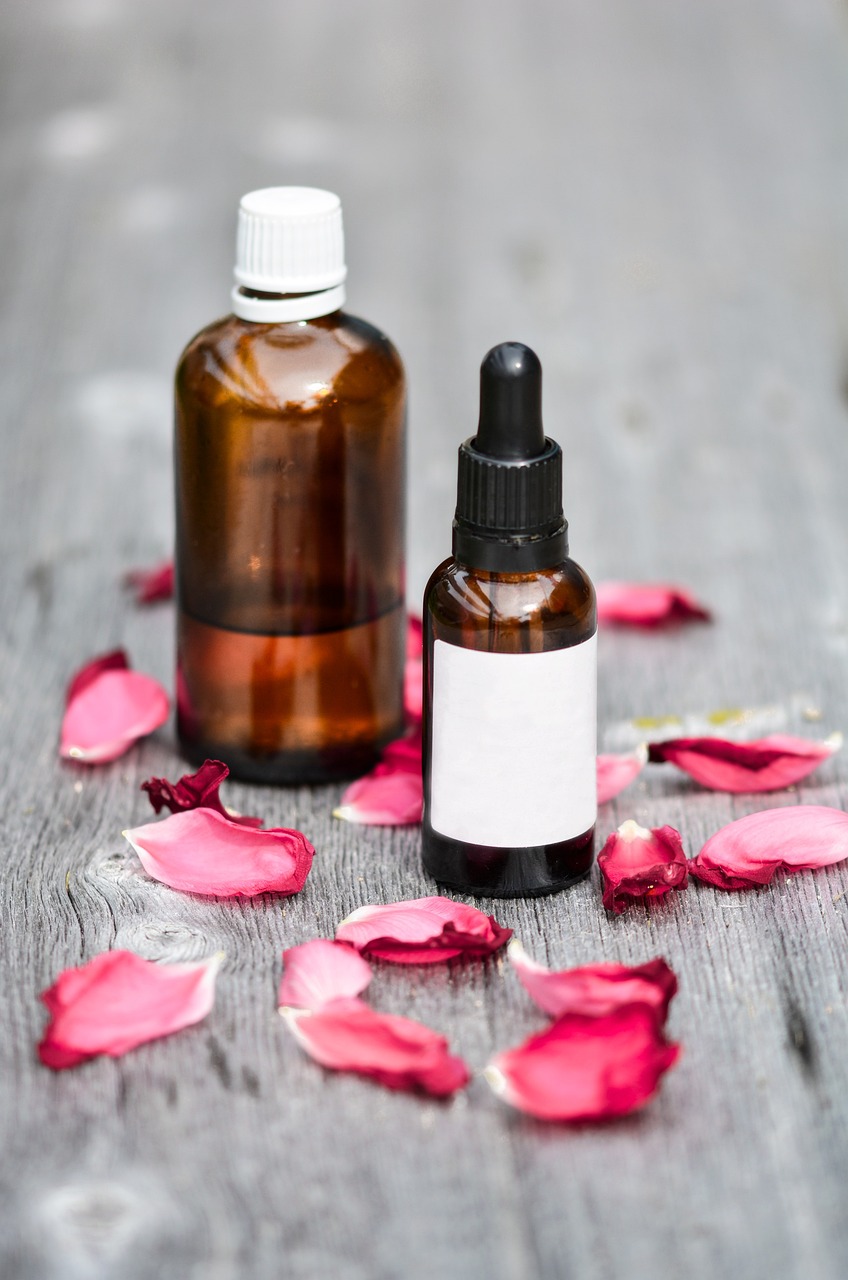 a bottle of essential oil next to a bottle of rose petals, shutterstock, product photo, on wooden table, set photo, professional product photo