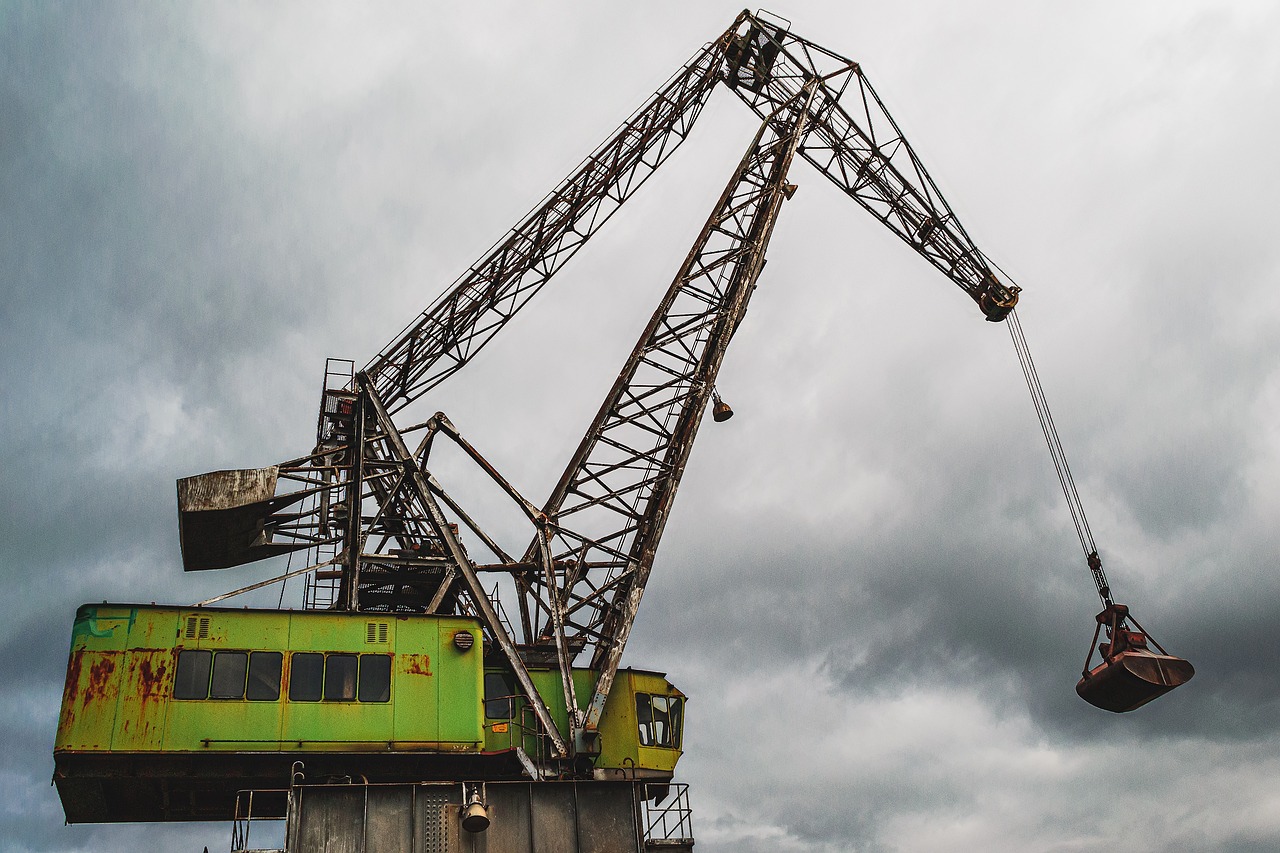 a crane that is sitting on top of a building, a stock photo, by Richard Carline, pexels contest winner, mining scrap metal, black and green scheme, on a cloudy day, side view close up of a gaunt