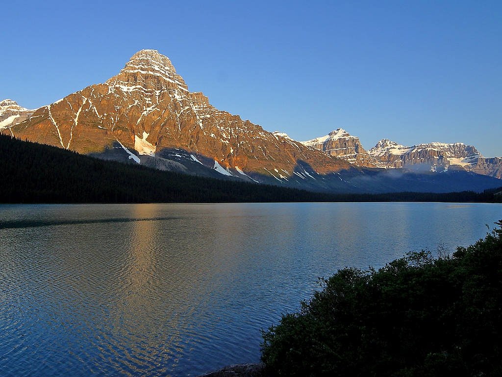 a large body of water with a mountain in the background, a photo, by Jim Nelson, pixabay, glacier national park, late afternoon sun, wikimedia commons, banff national park