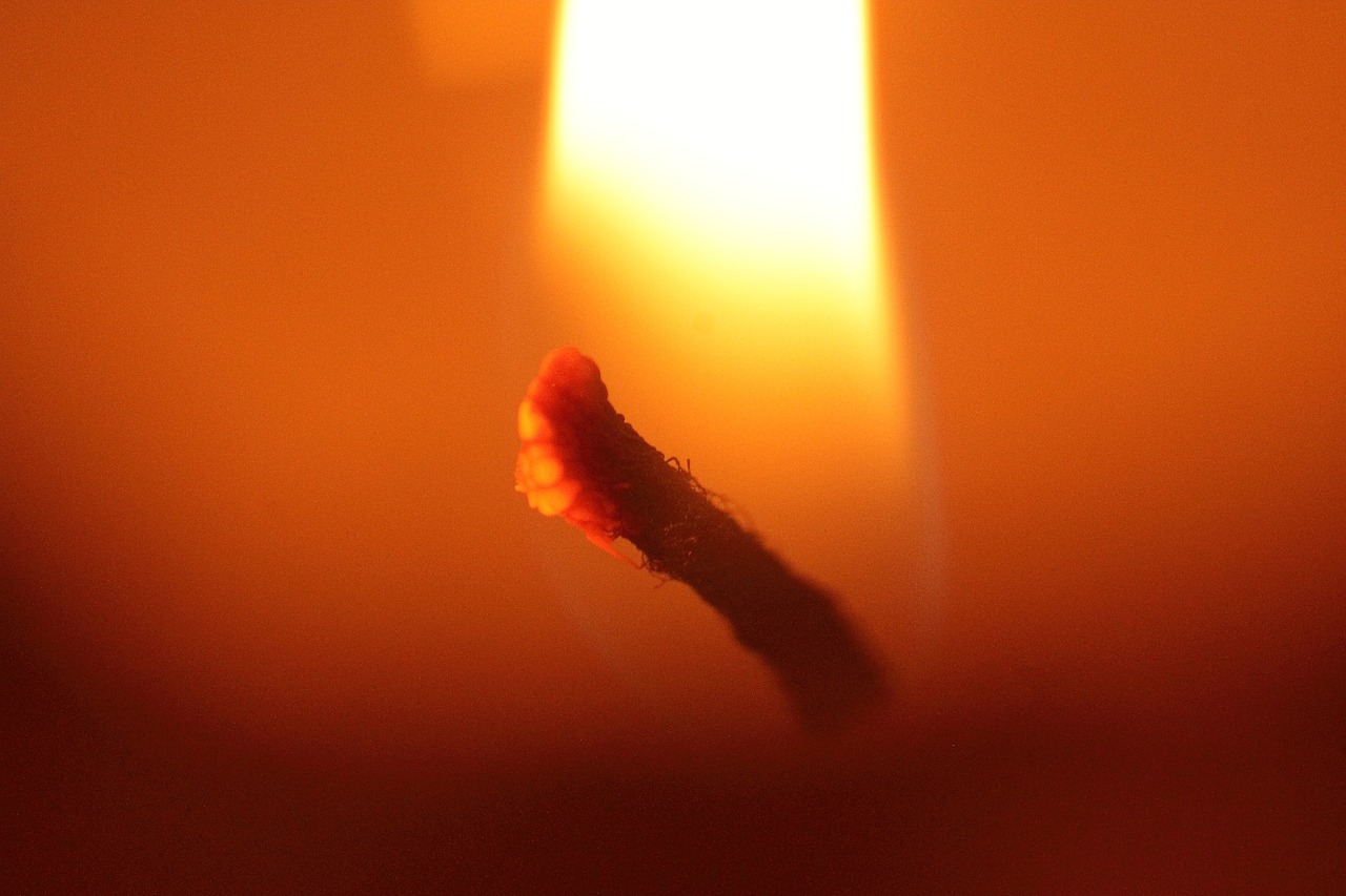 a close up of a candle with a lit candle in the background, a macro photograph, by Jan Rustem, in the elemental plane of fire, profile picture, hot glue, orange light