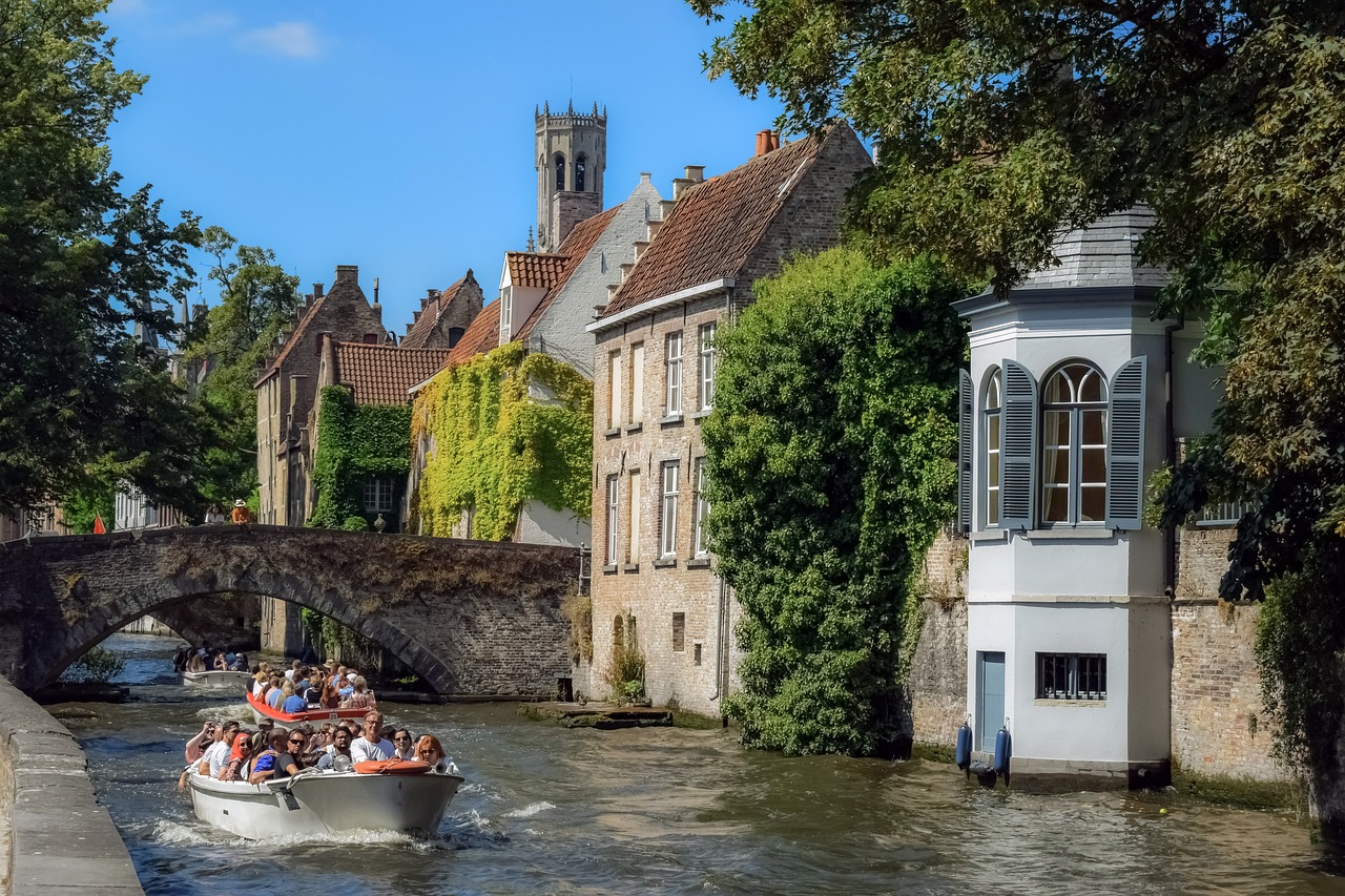 a group of people riding on top of a boat down a river, a photo, by Jan Tengnagel, shutterstock, renaissance, old abbey in the background, canal, photo taken from a boat, h 640