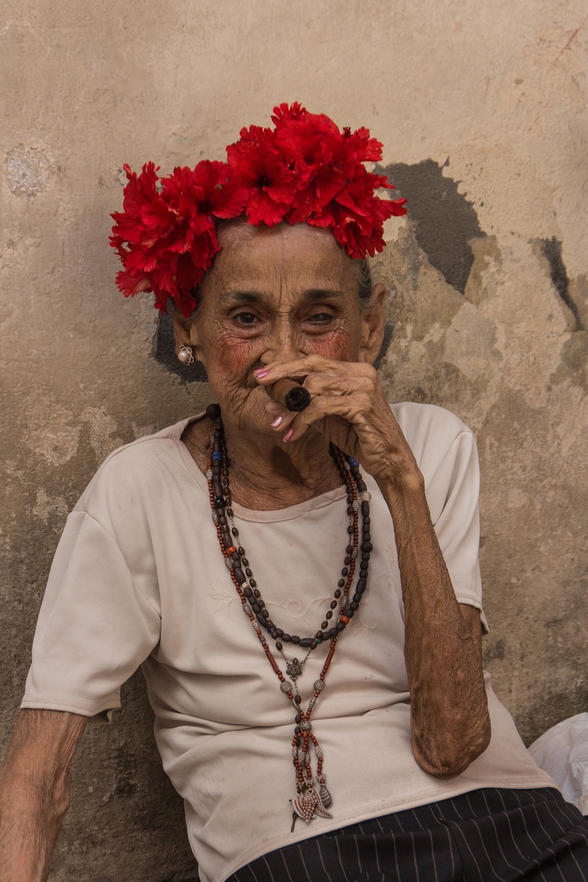 a woman with flowers in her hair smoking a cigarette, by Joze Ciuha, an old lady with red skin, cuban setting, photo taken in 2018, red adornements