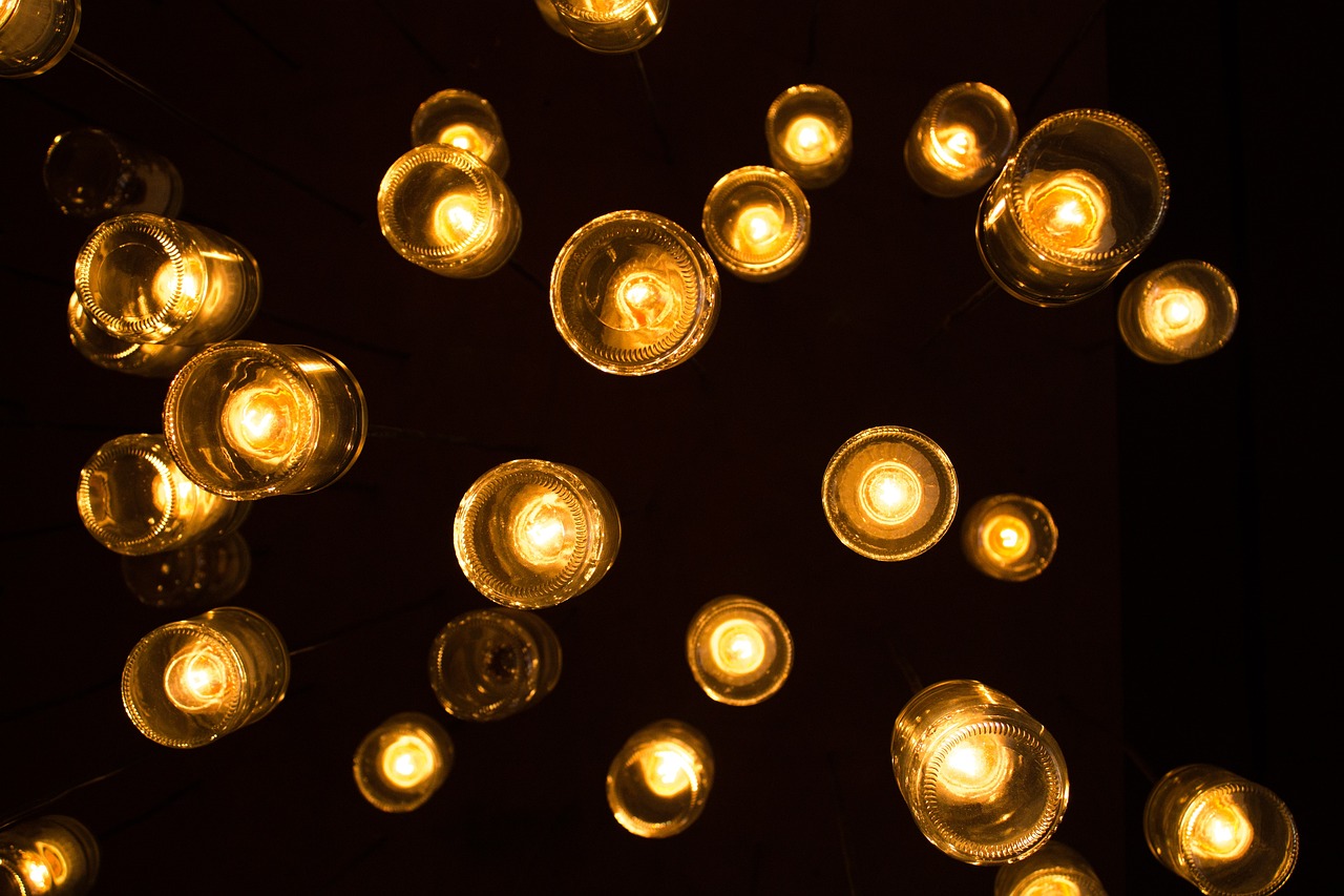 a bunch of light bulbs hanging from a ceiling, inspired by Bruce Munro, golden embers flying, natural candle lighting, light circles, golden dappled dynamic lighting