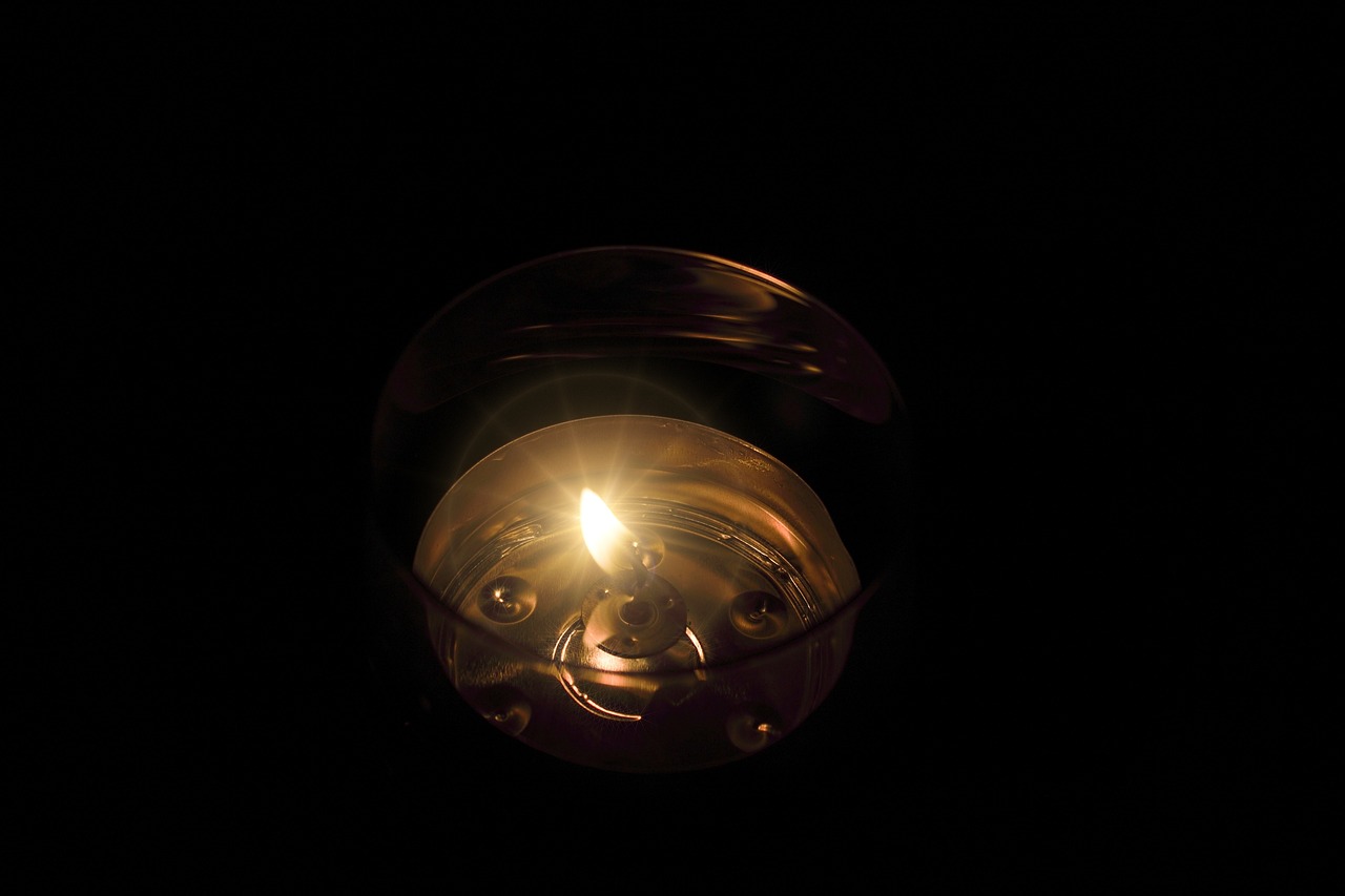 a close up of a lit candle in the dark, by Jan Rustem, flickr, light and space, inside glass orb, volumetric light ， surreal, istockphoto, glowing oil