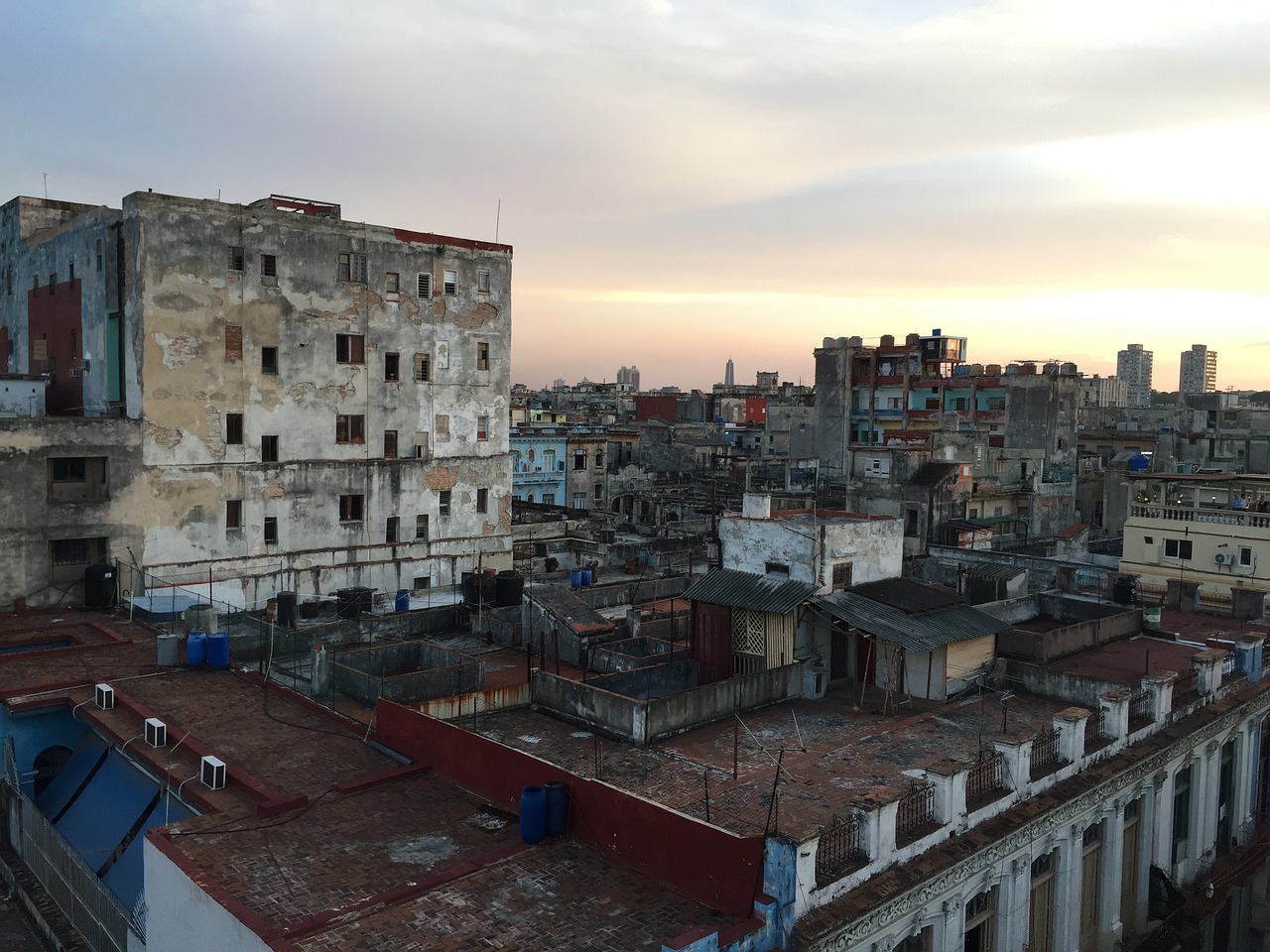 a view of a city from the top of a building, by Emanuel Witz, happening, cuban setting, poor lighting, rundown buildings, sun down