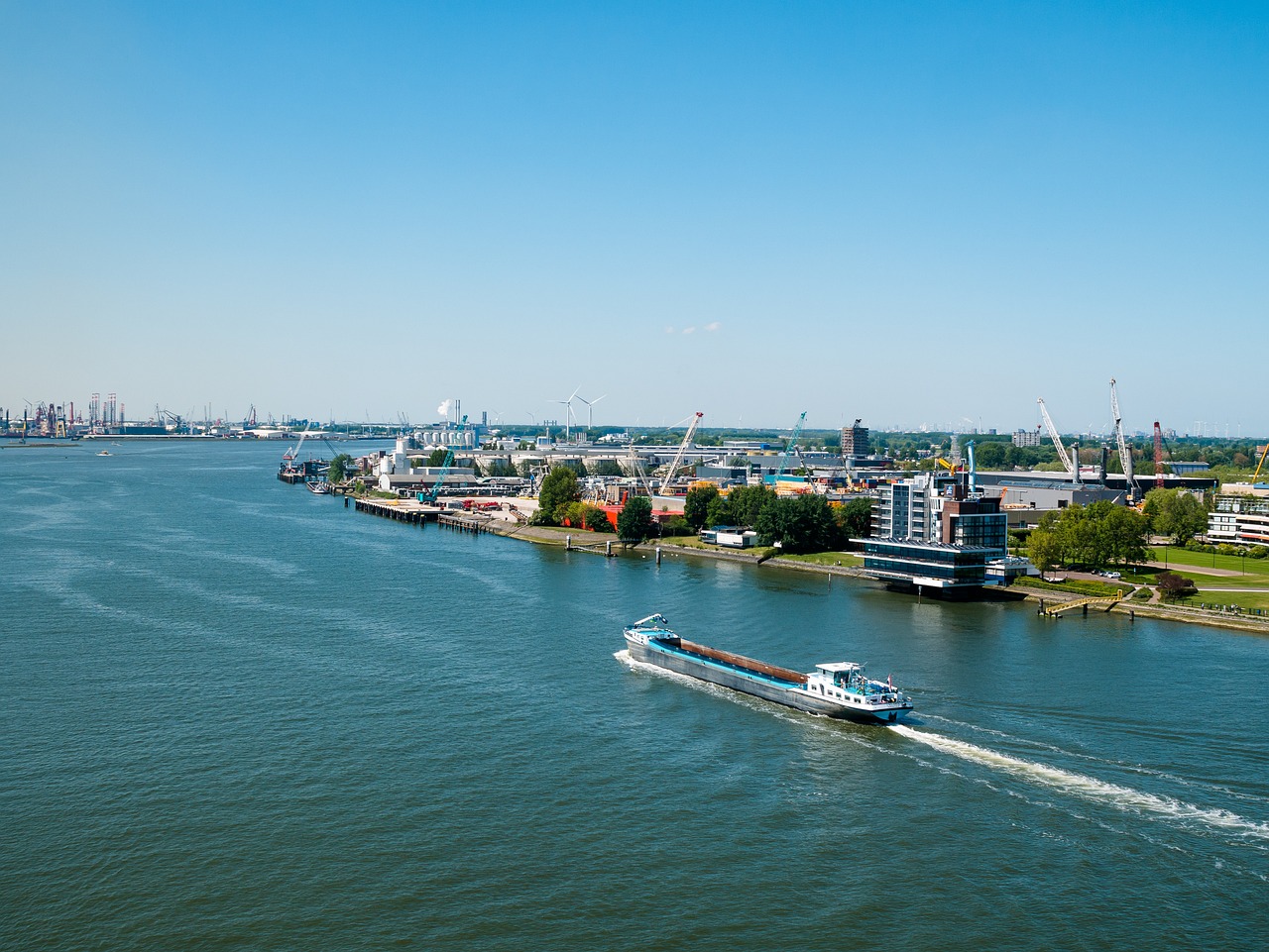a large boat traveling down a river next to a city, by Michiel van Musscher, shutterstock, shot from 5 0 feet distance, high quality photo, port scene background, wide long view