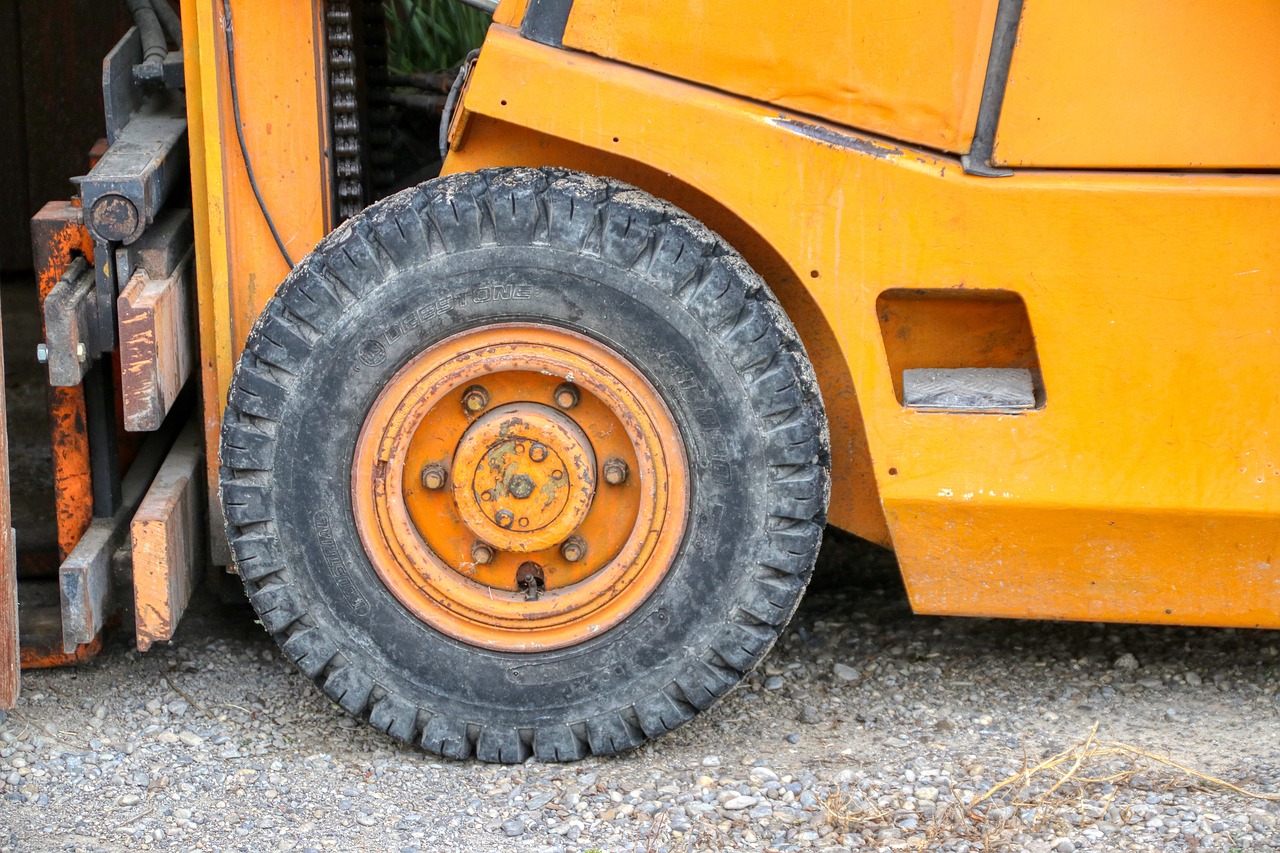 a close up of a tire on a forklift, by David Garner, auto-destructive art, an orange, 15081959 21121991 01012000 4k, older male, off - road