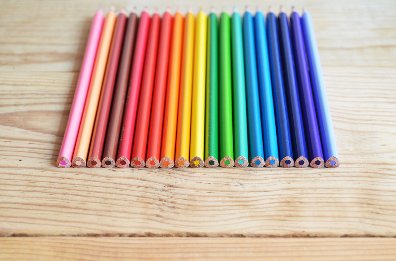 a group of colored pencils sitting on top of a wooden table, roygbiv, colouring page, product photography, colorful]”