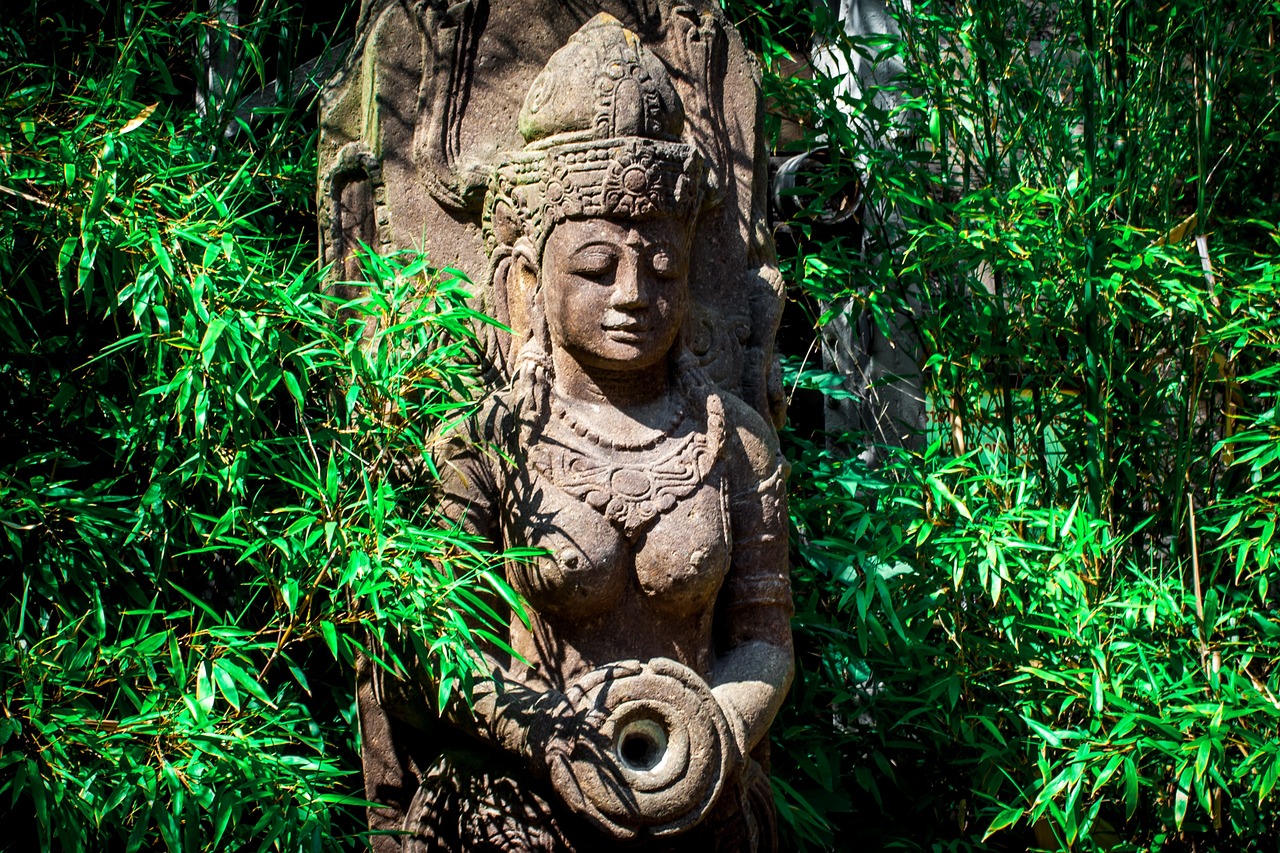 a statue sitting in the middle of a lush green forest, inspired by Li Di, shutterstock, sumatraism, flat shaped stone relief, dark skin female goddess of love, very very well detailed image, bamboo