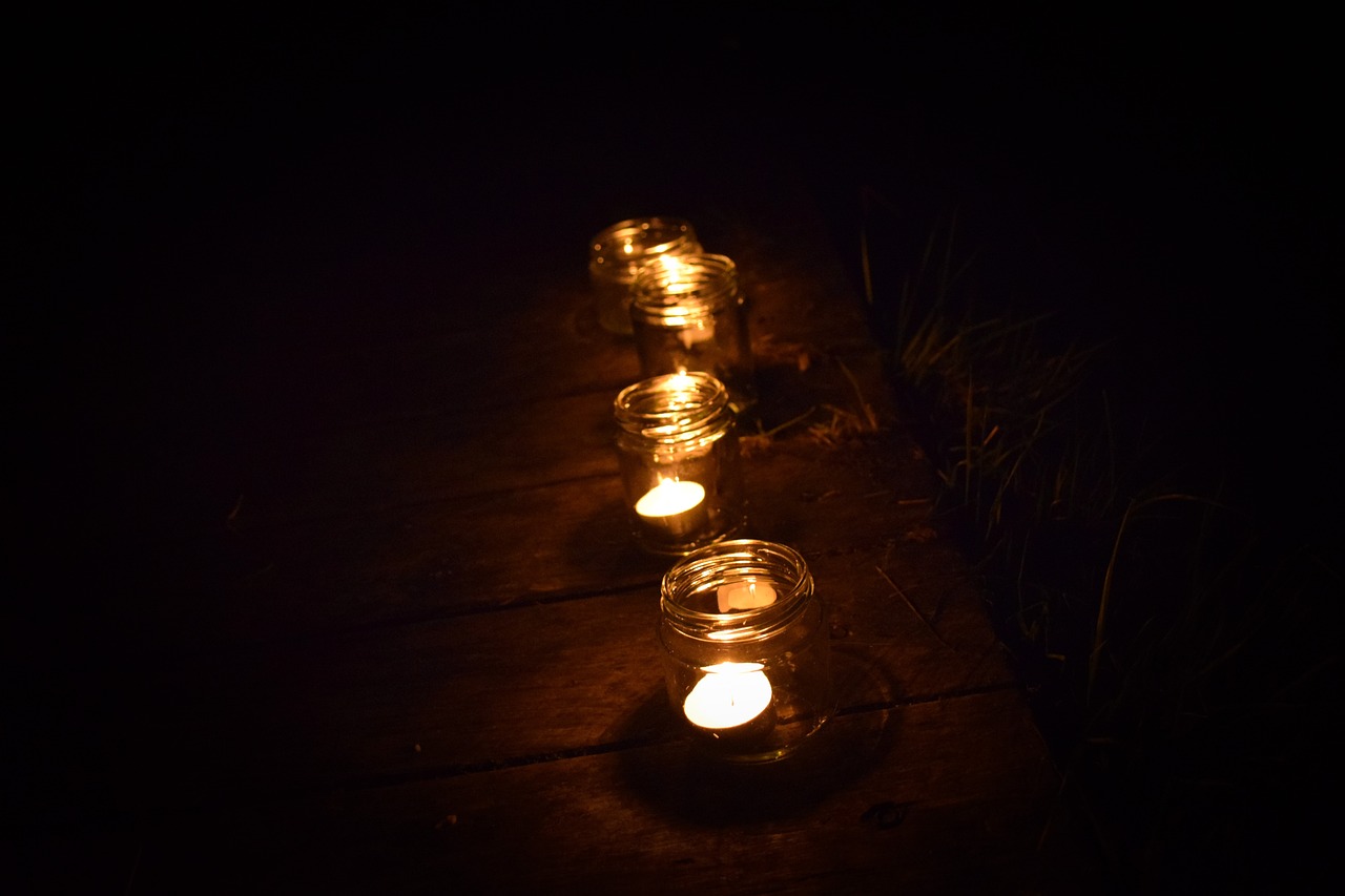 a row of candles sitting on top of a wooden table, by Alice Mason, night outdoors, paths, glowing jar, night photo