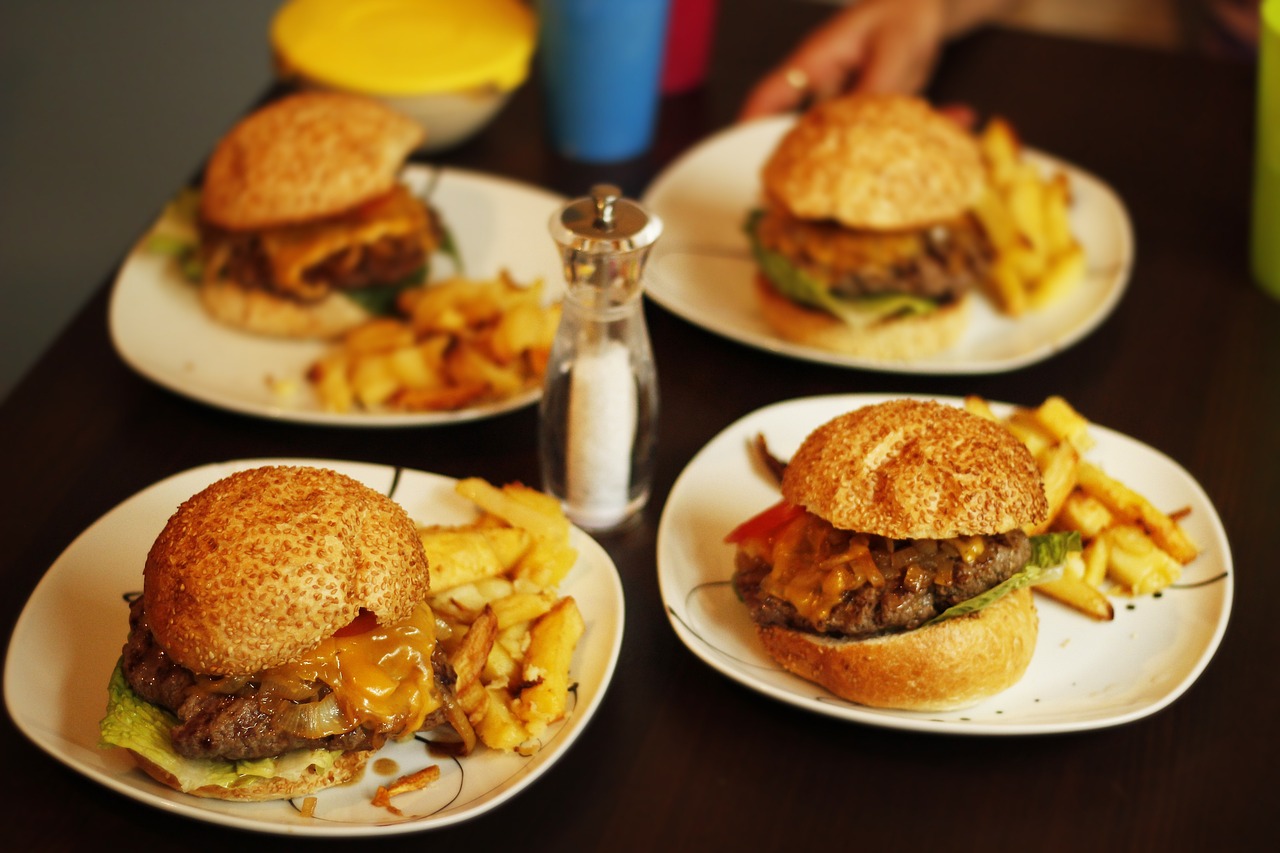a close up of three plates of food on a table, a picture, by Joe Bowler, pexels, cheeseburger, family dinner, wide angle”, full res