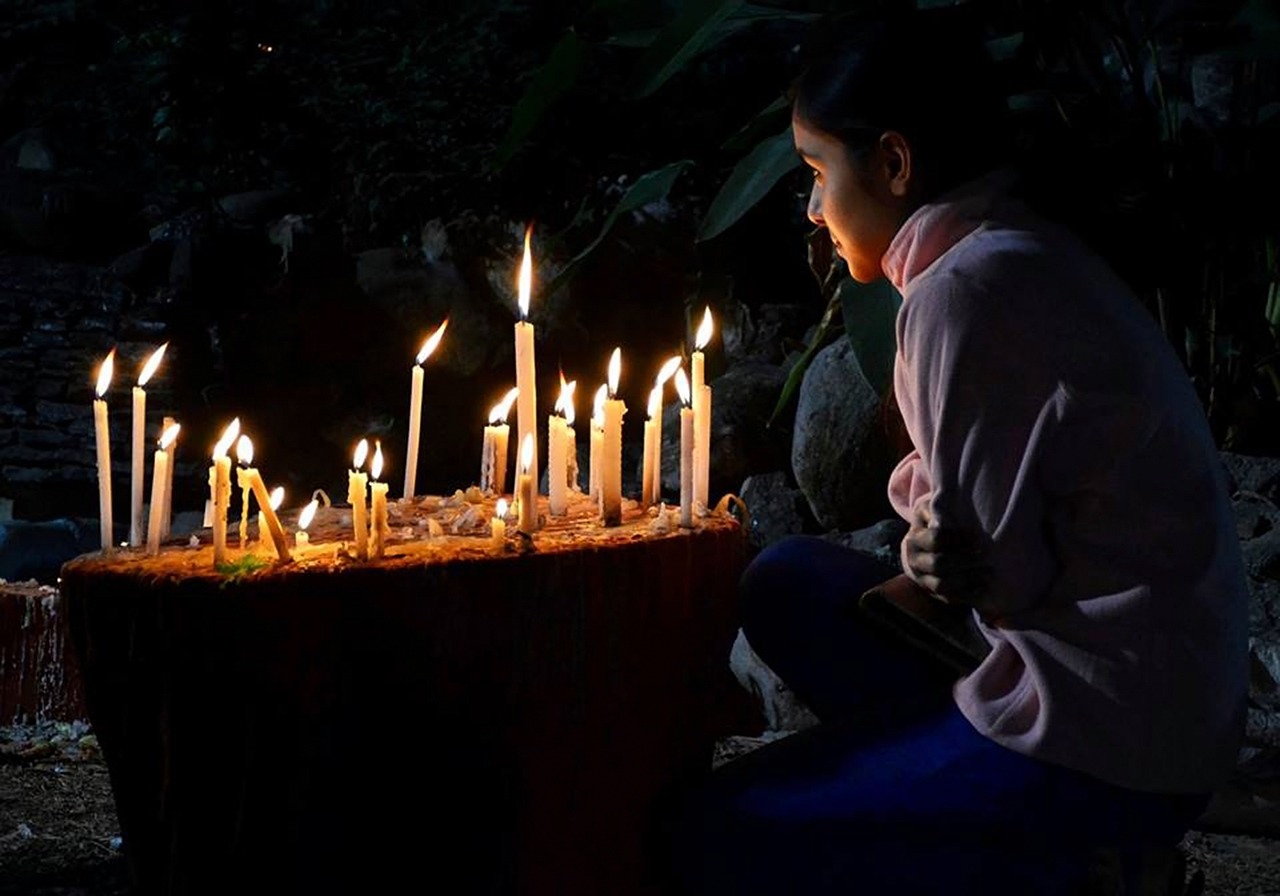 a woman kneeling in front of a cake with lit candles, kuntilanak on bayan tree, photograph credit: ap, laos, profile pic
