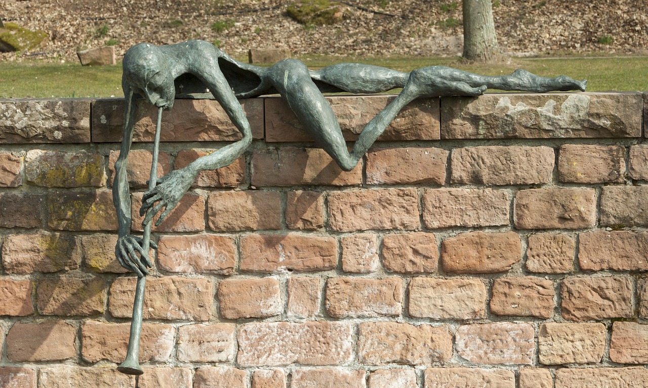 a statue sitting on top of a brick wall, a surrealist sculpture, inspired by Sir Jacob Epstein, pexels, new sculpture, swinging on a vine over a chasm, detmold charles maurice, draped with horrors and spines, detail