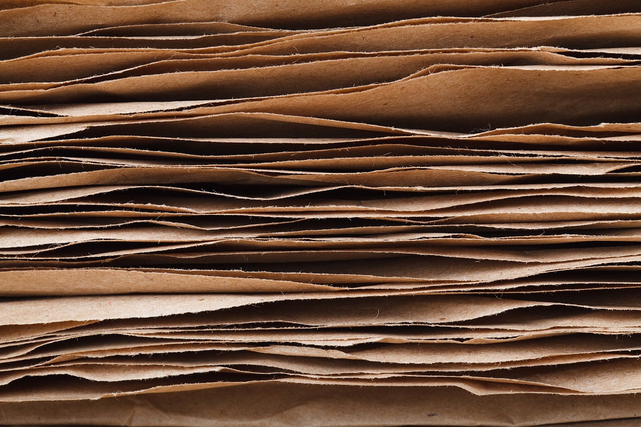 a stack of brown paper sitting on top of a table, pexels, highly detailed panel cuts, epicanthal fold, streamlined spines, mobile wallpaper