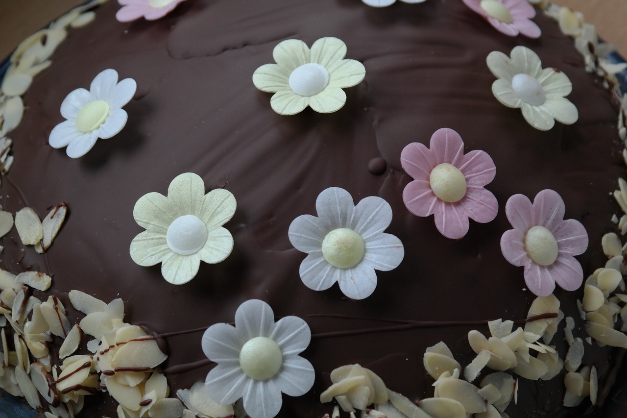 a chocolate cake decorated with white and pink flowers, a pastel, by Sylvia Wishart, flickr, flower power motifs, round-cropped, flower petals, buttercups