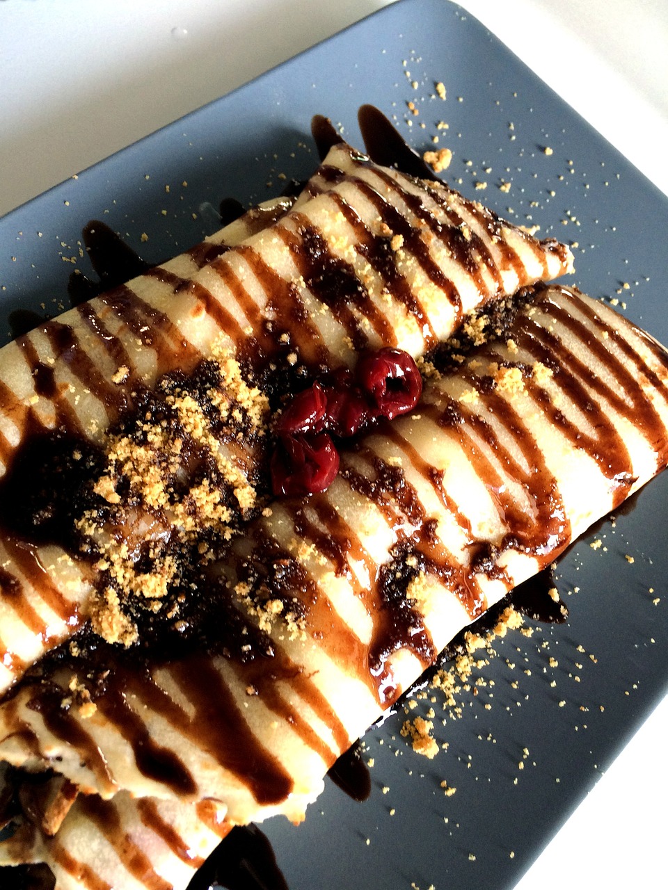 a dessert sitting on top of a blue plate, by Lee Loughridge, pixabay, some chocolate sauce, taco, maple syrup highlights, maroon