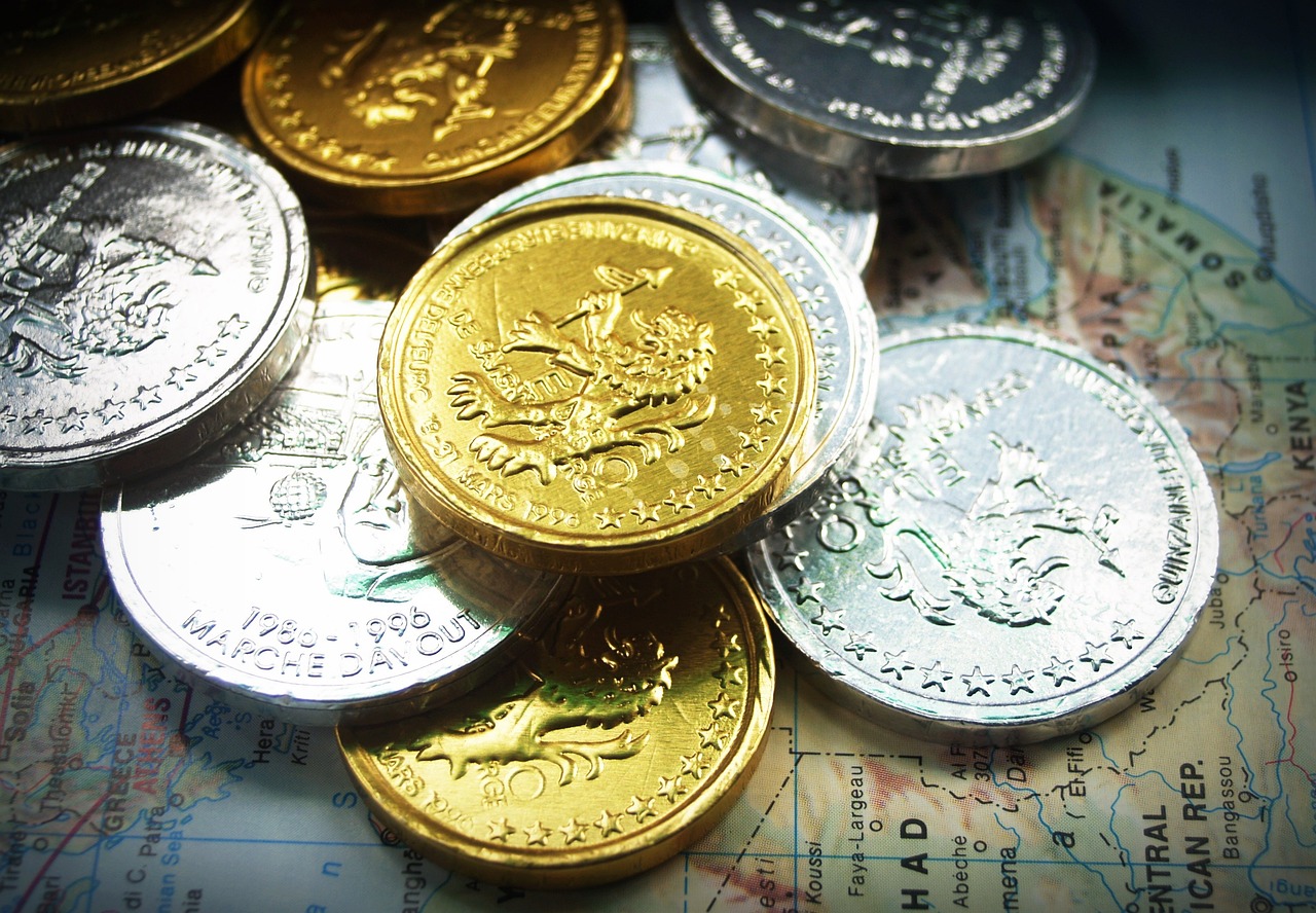 a bunch of coins sitting on top of a map, by Walenty Wańkowicz, gold and silver and brass, closeup!!!!!!, adventurer, olympics