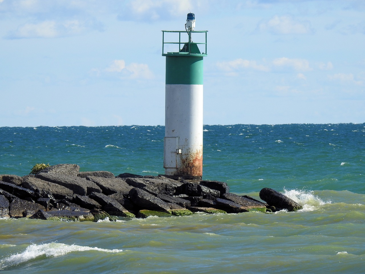 a lighthouse in the middle of a body of water, a picture, figuration libre, closeup photo, in sunny weather, greenish tinge, pillar