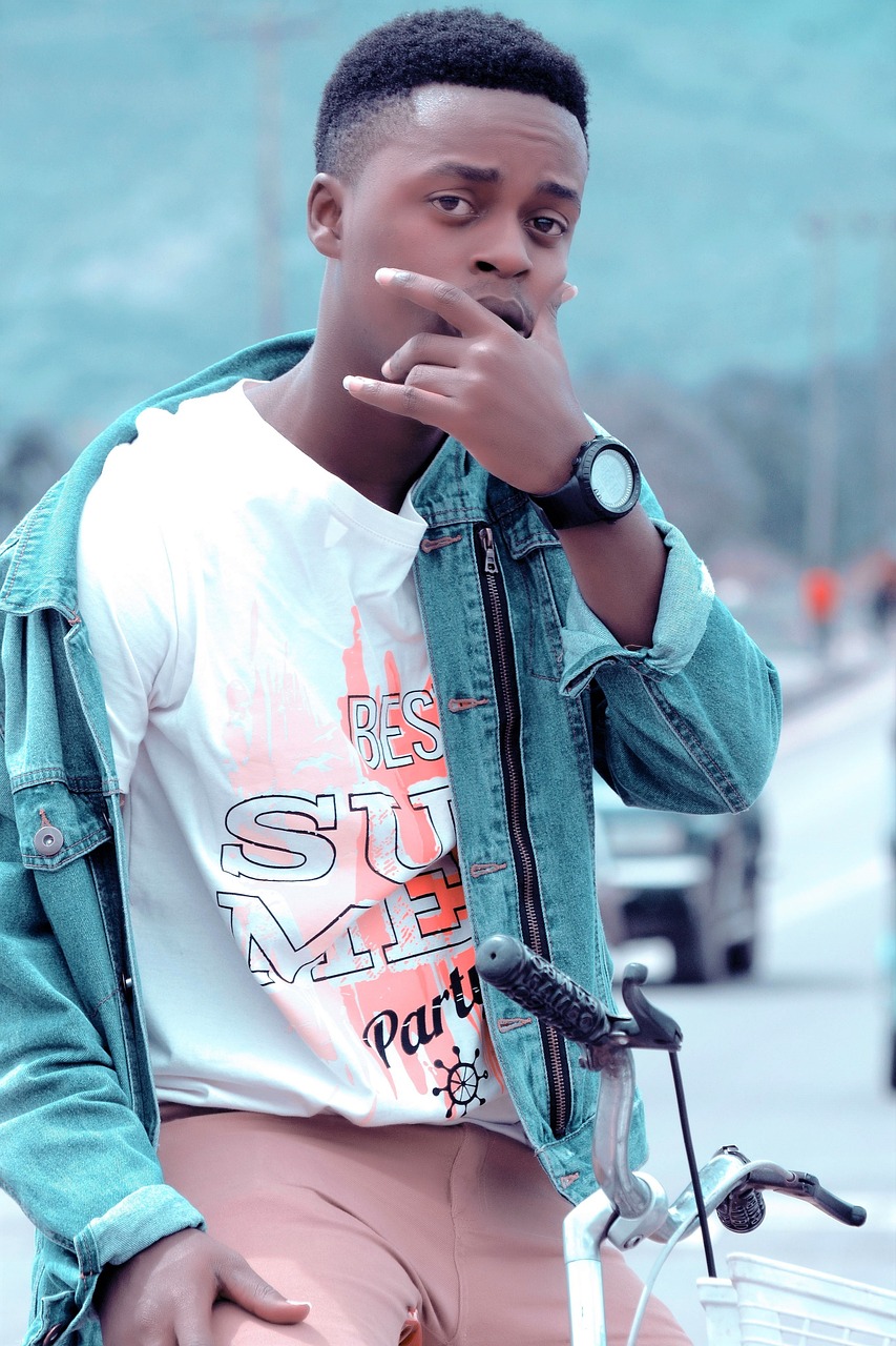 a man standing next to a bike smoking a cigarette, an album cover, by Afewerk Tekle, pexels, attractive young man, on a road, casual pose, wearing a shirt and a jean