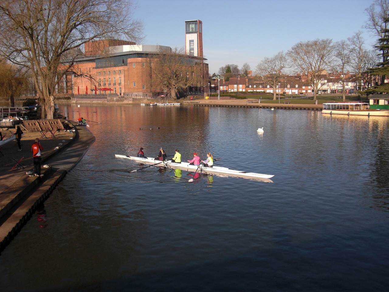 a group of people rowing down a river, by Peter Prendergast, flickr, in an urban setting, february), lakeside, rose