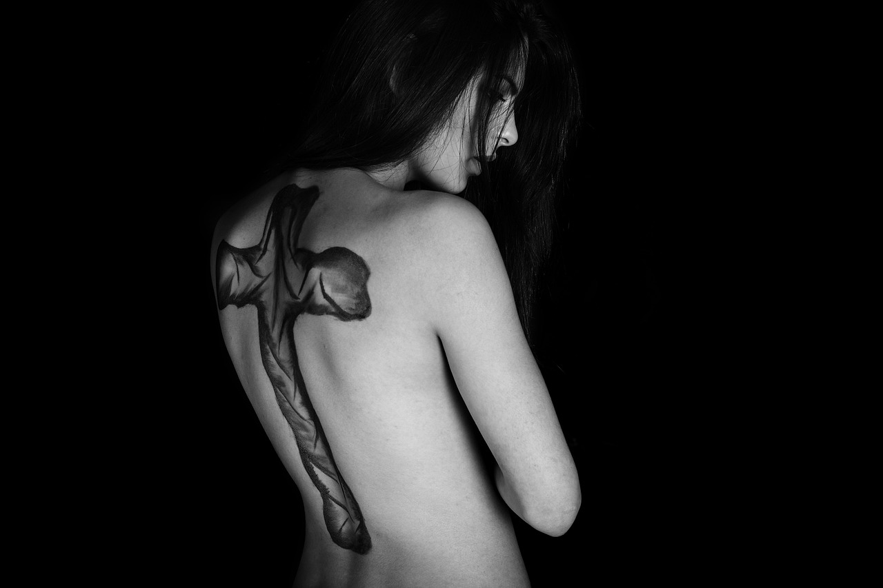 a woman with a tattoo on her back, a tattoo, by Adam Marczyński, art photography, cross, draconian, dark negative space, lamia