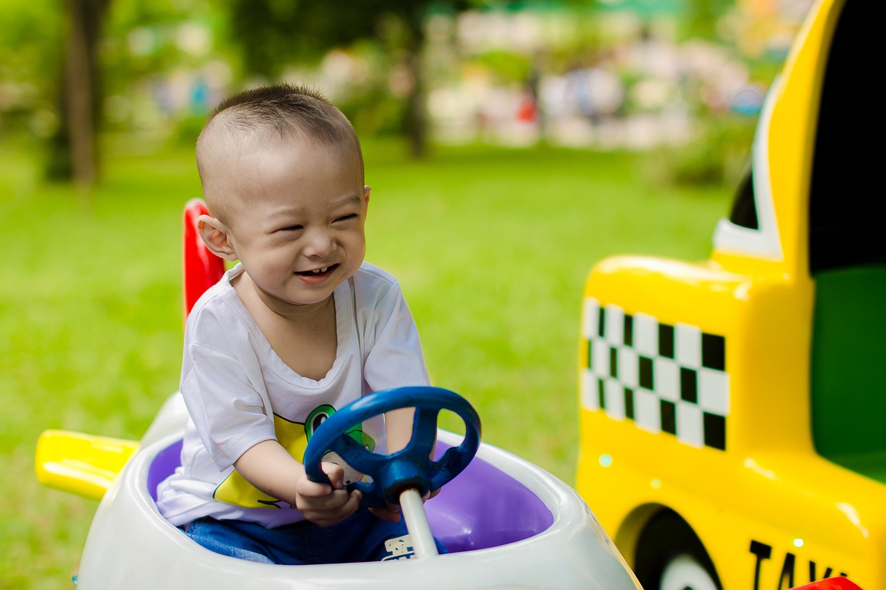 a baby sitting in a toy car with a steering wheel, a picture, by Yi Jaegwan, pexels, toyism, grinning lasciviously, taxis, square, yanjun chengt