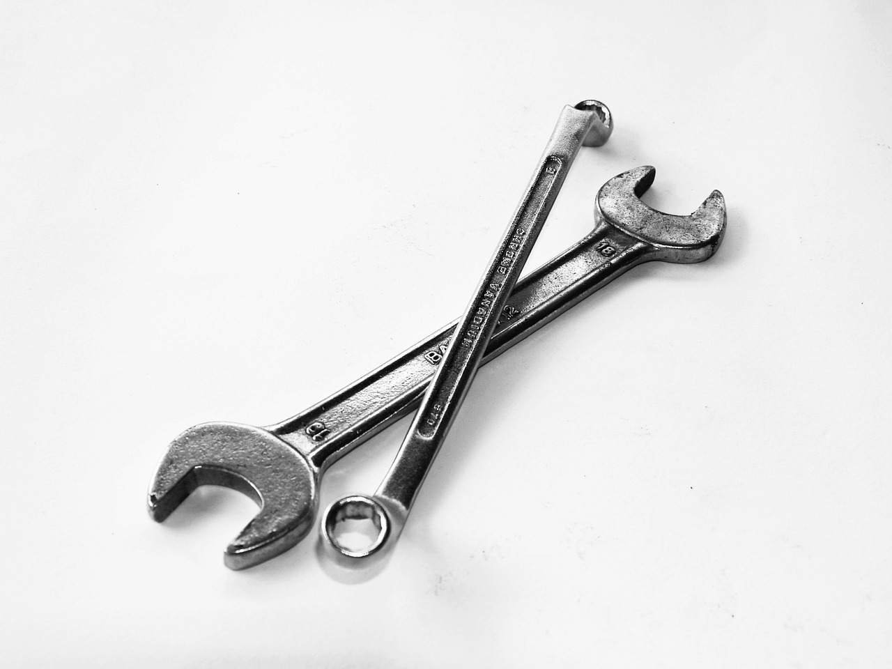 two wrenches sitting next to each other on a table, minimalism, on a white background, made out of shiny white metal, blanco y negro, maintenance photo