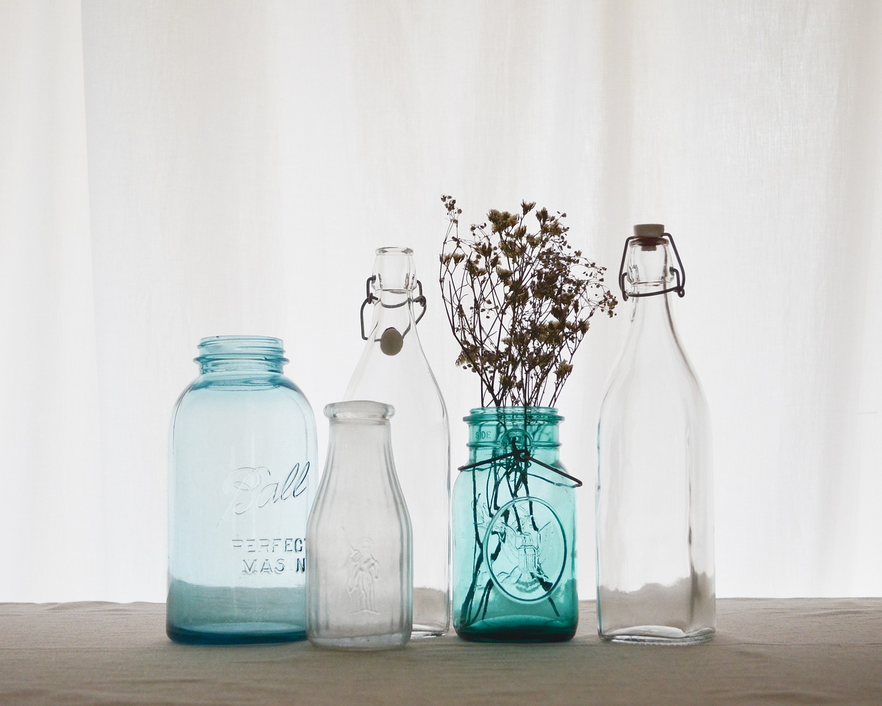 a group of vases sitting on top of a table, a still life, unsplash, inside a glass jar, blueish, vintage old, soda