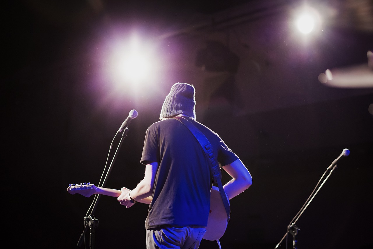 a man that is standing in front of a microphone, a picture, by Neil Blevins, the guitar player, shot from the back, student, stage lighting