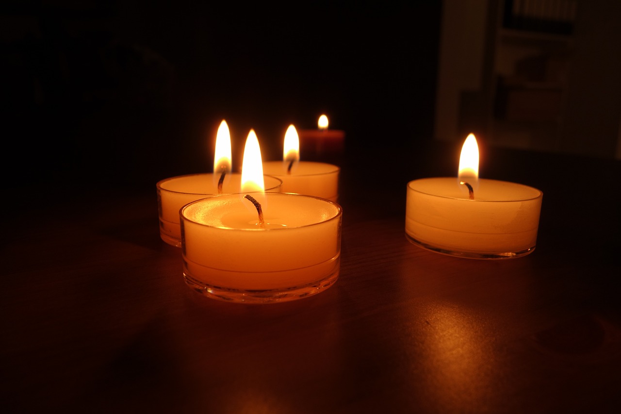 a close up of three lit candles on a table, a picture, night photo, high res photo