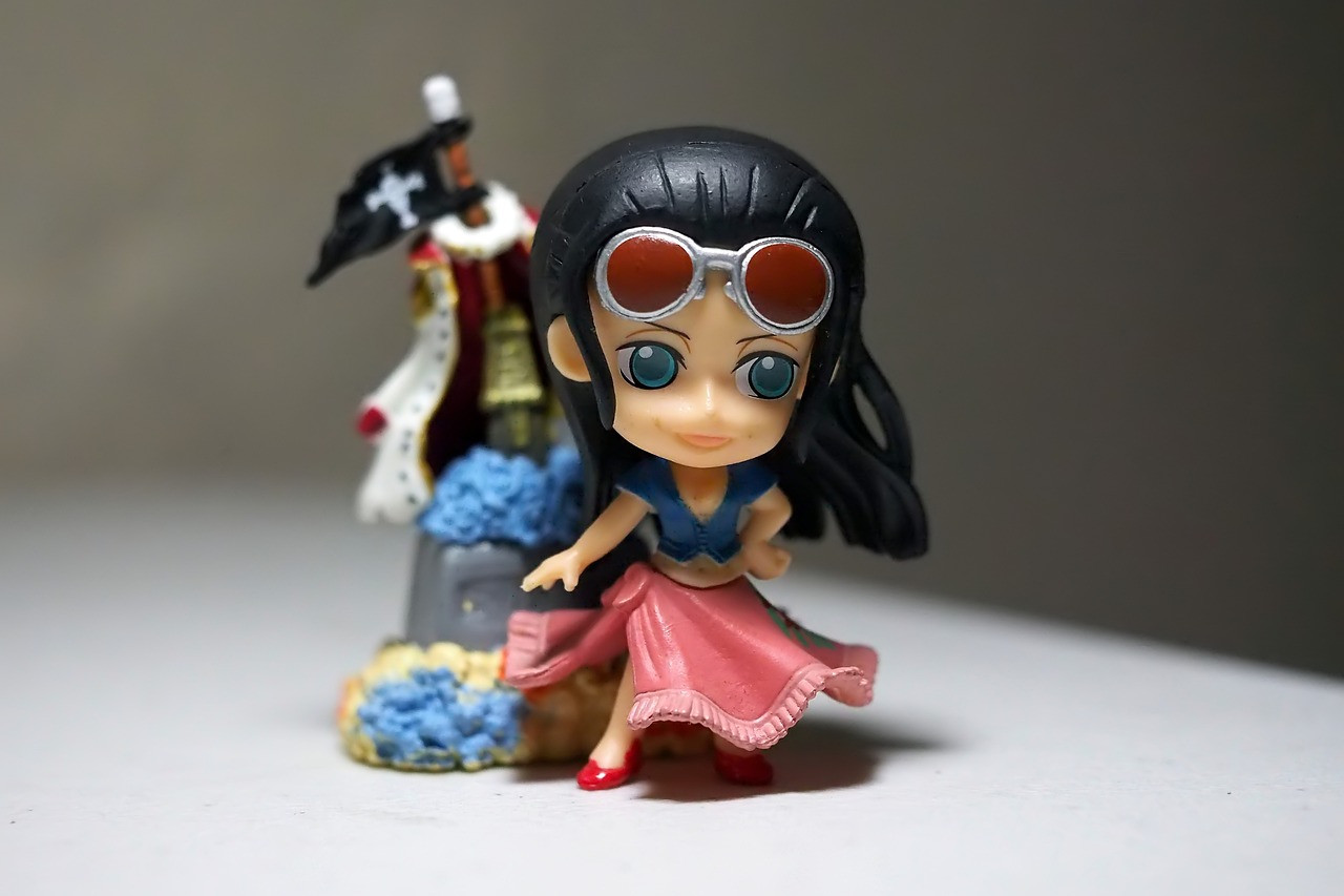 a couple of figurines sitting on top of a table, a picture, inspired by Eiichiro Oda, her black hair is a long curly, portrait mode photo, jumping towards viewer, with sunglass