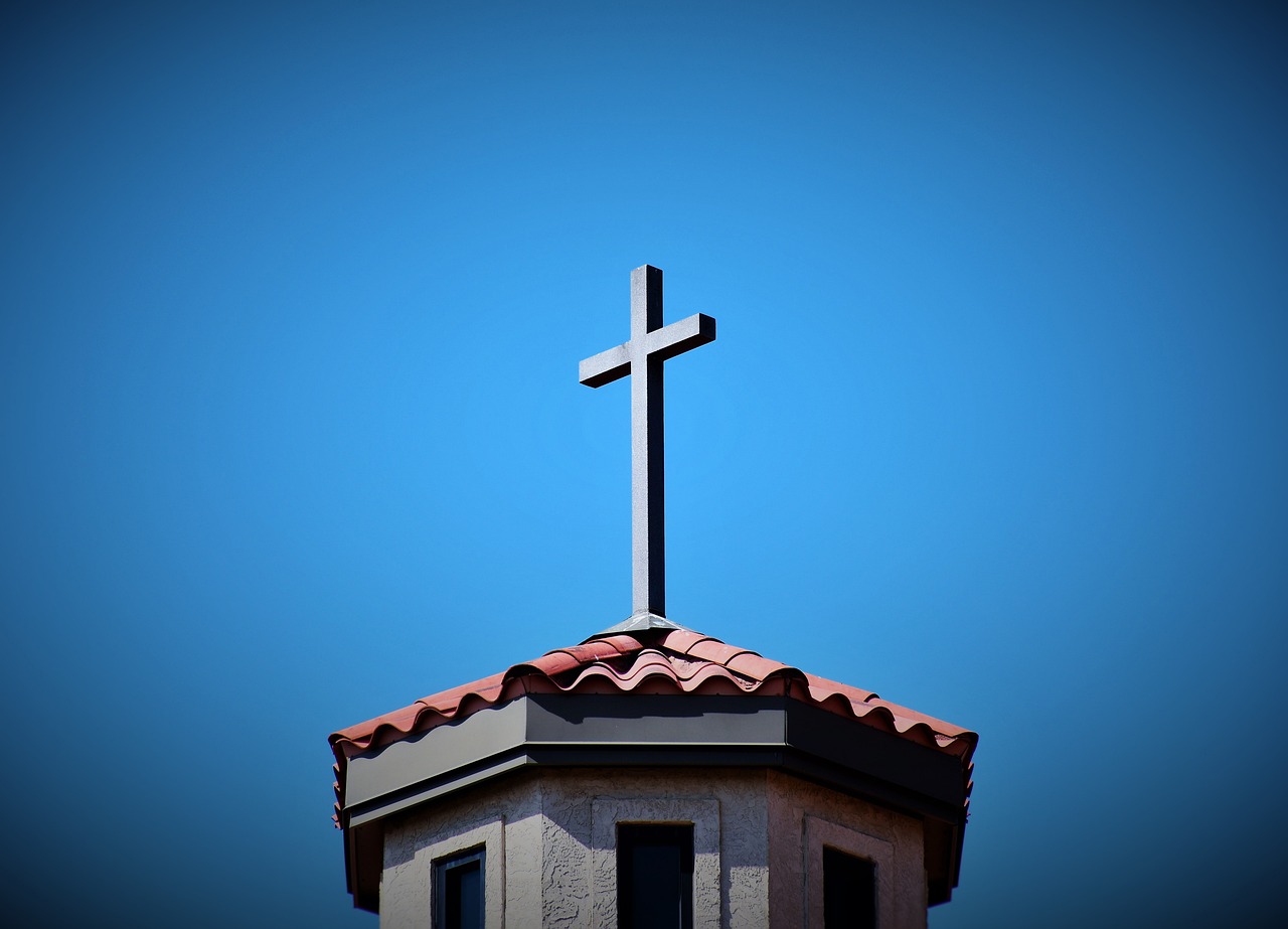 a cross on top of a building with a blue sky in the background, a photo, california;, against dark background, closeup photo, in a sanctuary