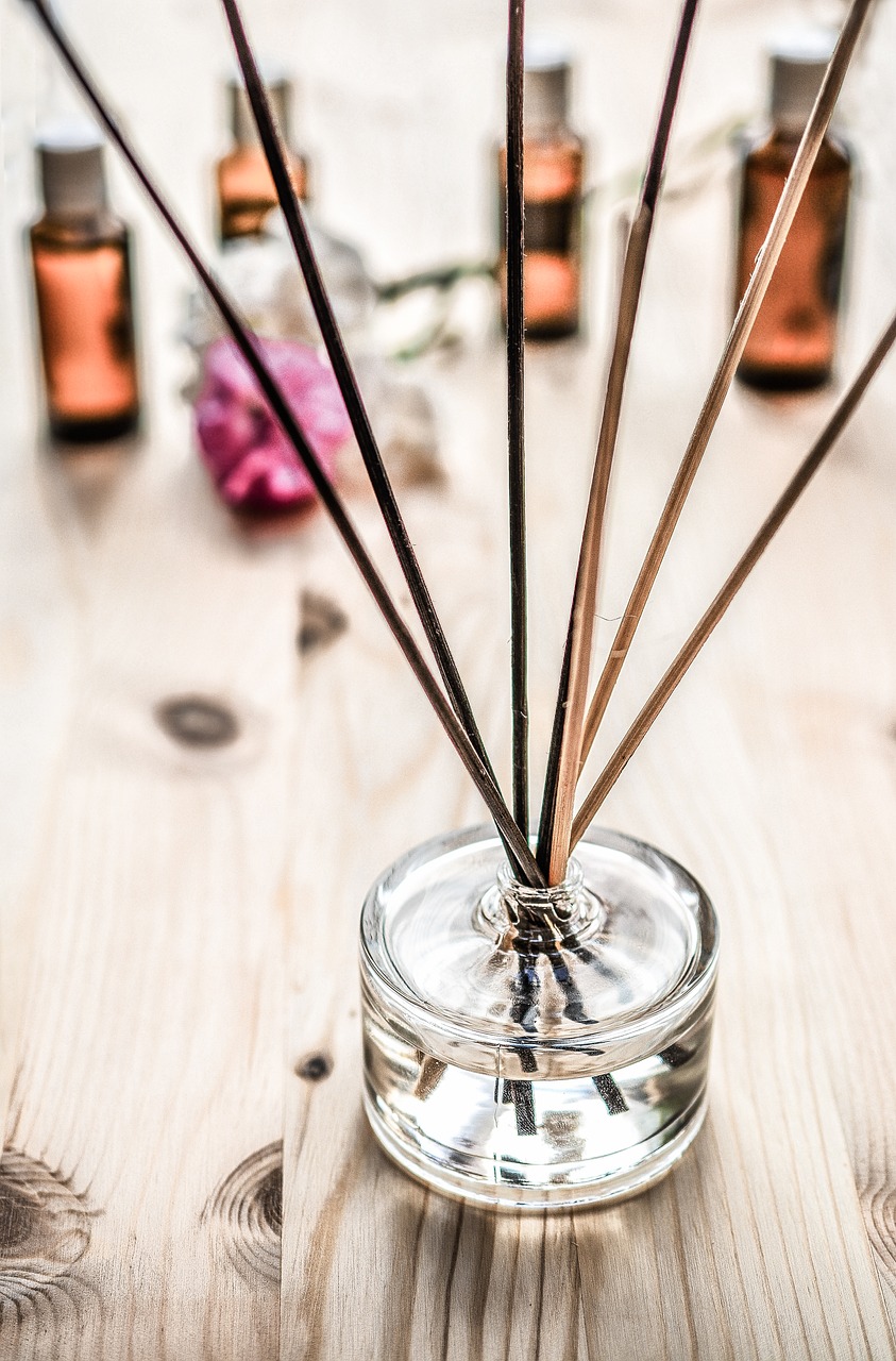 a glass jar filled with reeds sitting on top of a wooden table, visual art, candy treatments, fumes, sleek spines, flower power