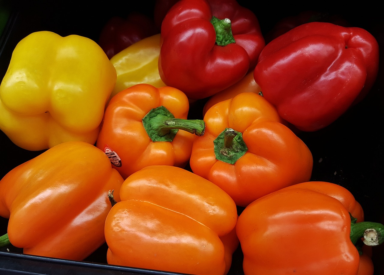 a bin filled with lots of different colored peppers, a picture, precisionism, light orange values, close-up product photo, a brightly coloured, taken from the high street