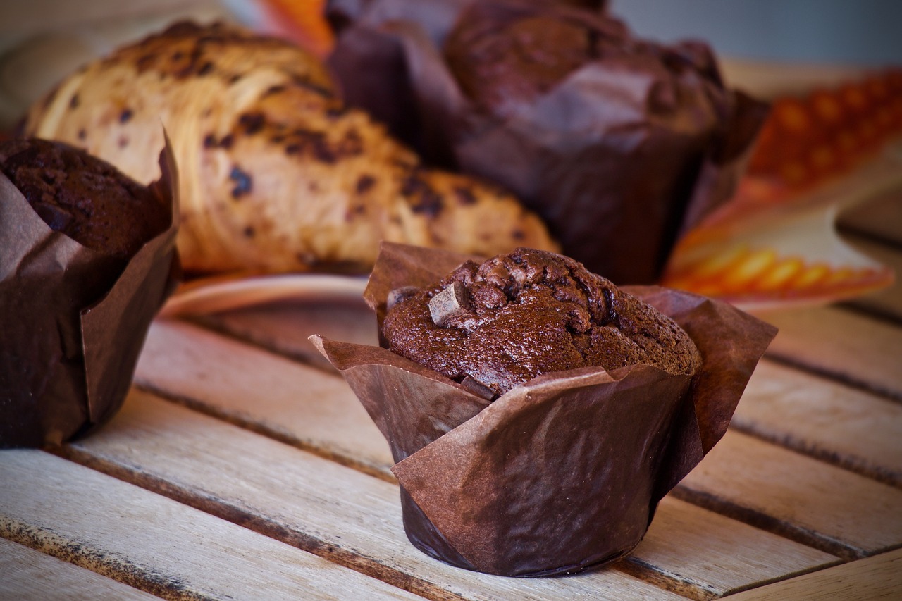 a couple of muffins sitting on top of a wooden table, by Aleksander Gierymski, shutterstock, chocolate. highly detailed, cone, brown bread with sliced salo, voge photo