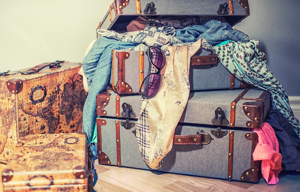 a pile of luggage sitting on top of a hard wood floor, a stock photo, shutterstock, sunglasses and a scarf, vintage color photo, exiting from a wardrobe, messy bed
