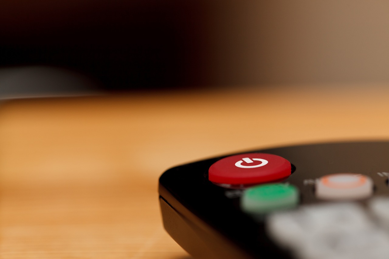 a remote control sitting on top of a wooden table, pexels, sitting on a red button, dynamic closeup, still image from tv series, banner