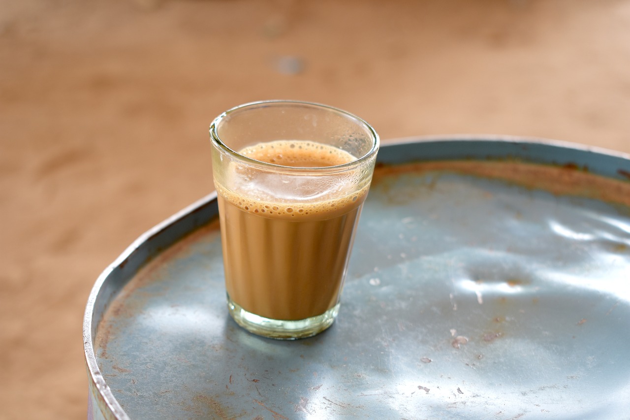 a glass of coffee sitting on top of a metal barrel, hurufiyya, indian, image, milk, homemade