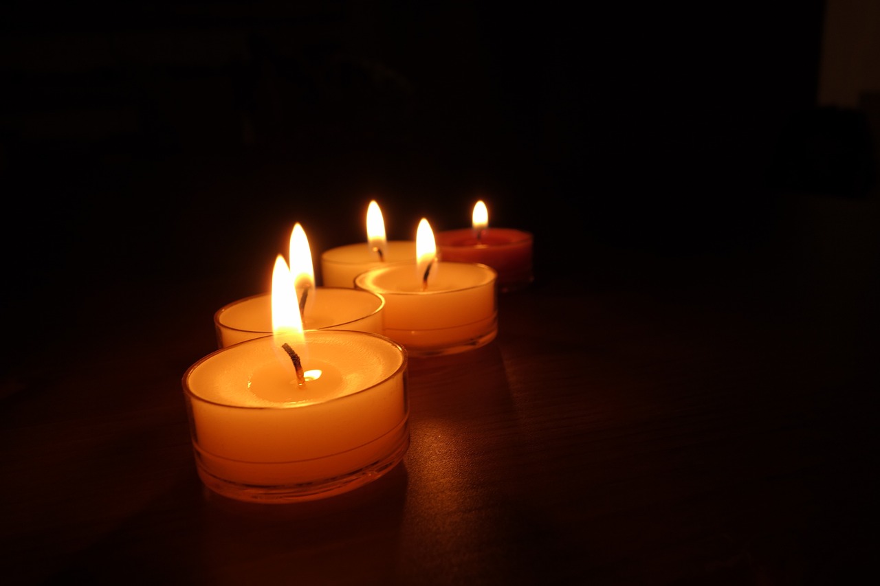 three lit candles sitting on top of a wooden table, a picture, night photo, in a row, low angle photo