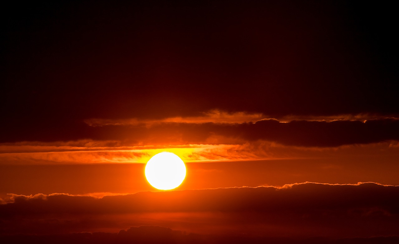 the sun is setting behind the clouds in the sky, by Hans Schwarz, bright yellow and red sun, red sun, f/3.5, warm golden backlit