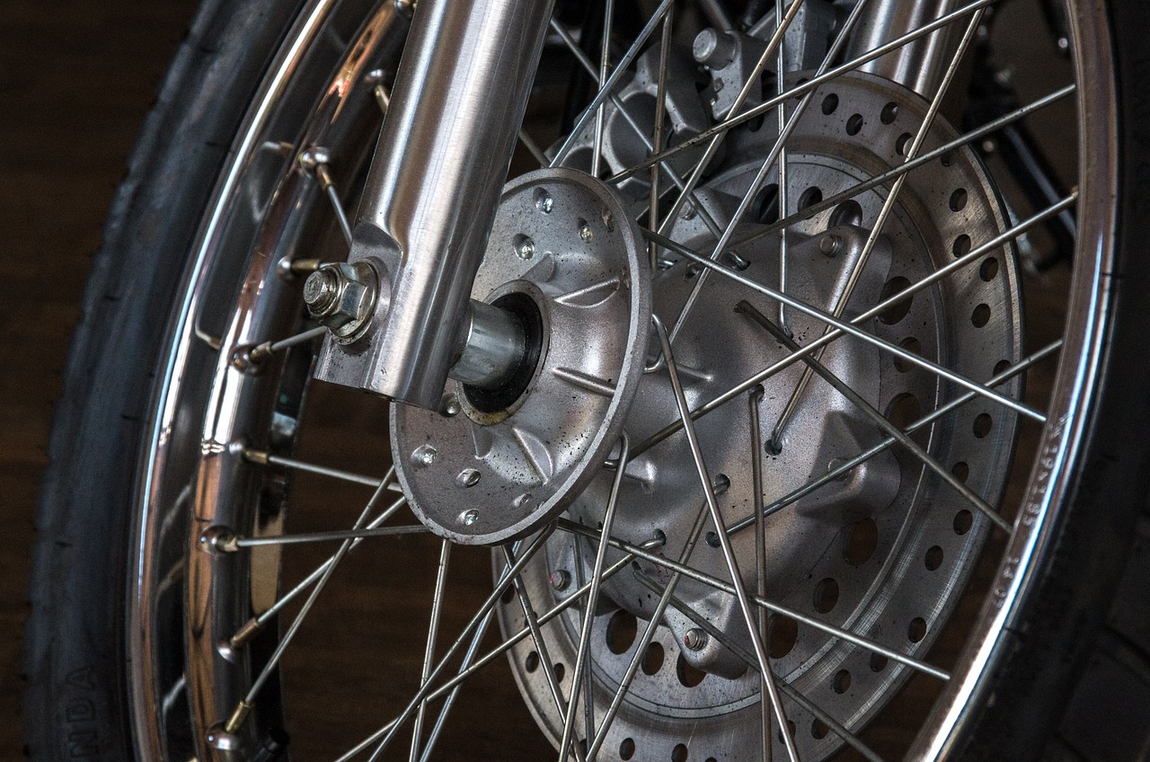 a close up of a motorcycle tire on a wooden floor, bauhaus, intricate mechanisms, abcdefghijklmnopqrstuvwxyz, chromed metal, detailed - wheels