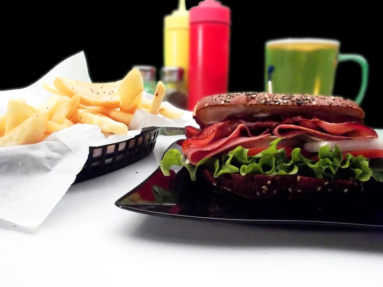 a sandwich sitting on top of a black plate next to a basket of chips, photorealism, restaurant menu photo, ((oversaturated)), foodphoto, red skinned